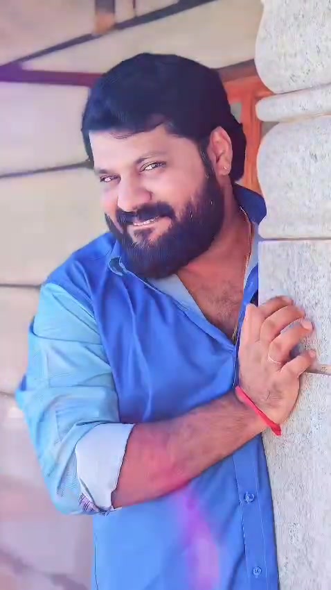 Rahul in a blue shirt beside a stone pillar